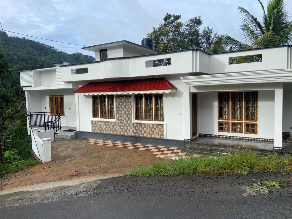 een wit huis met een rode luifel bij The Lovely Home Stay in Munnar