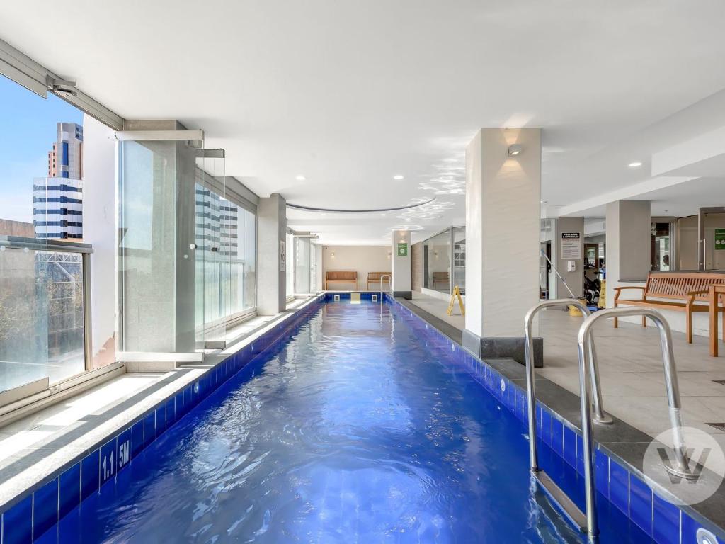 a large pool in a building with blue water at 2-Bed City Retreat with Gym and Pool Access in Adelaide