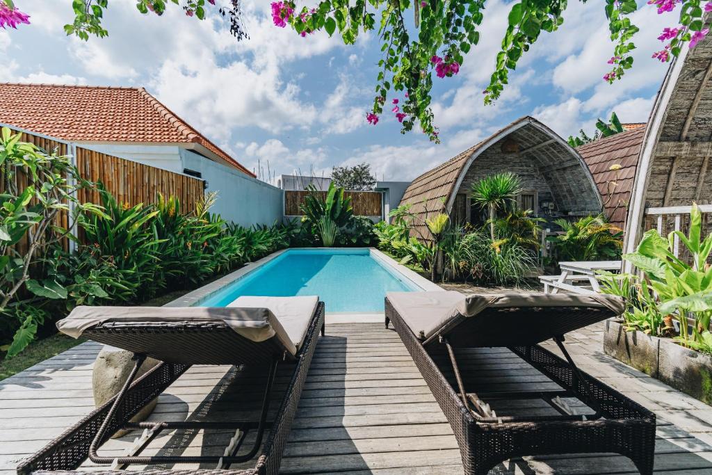 a swimming pool with two chairs next to a house at Sunshine Village Canggu in Canggu