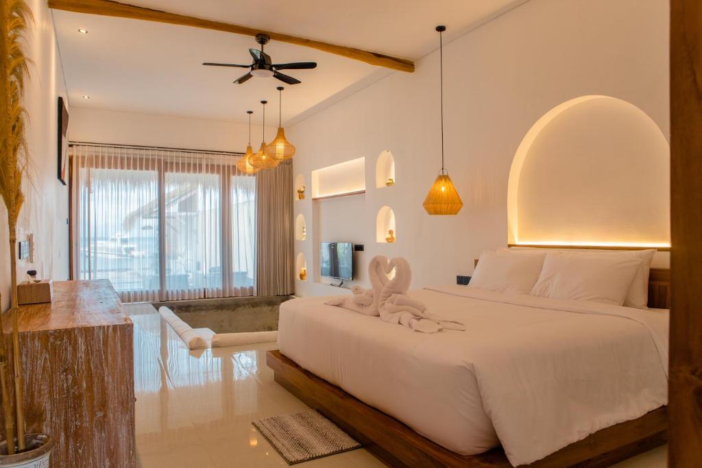 a bedroom with a large white bed with a ceiling fan at Miwa Bali Villa in Nusa Penida
