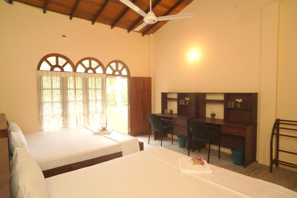 ein Schlafzimmer mit einem Bett, einem Schreibtisch und einem Tisch in der Unterkunft Sanmi Runway View Resort in Kimbulapitiya