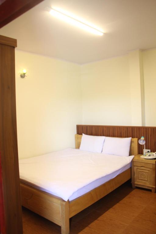 a bed with white sheets and pillows in a room at Thu Van Apartment in Xuan An