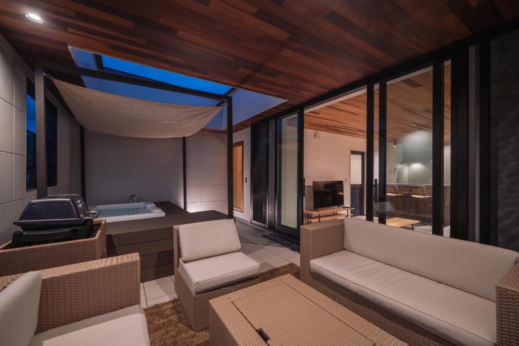 a room with a couch and chairs and a tub at Sanctuary Villa & Sauna Ogimi by Relapool in Banchi
