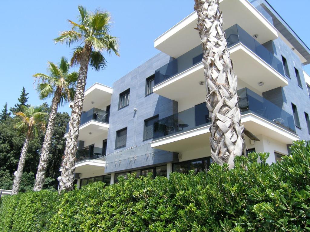 an apartment building with palm trees in front of it at Apartments Mon Amour in Dubrovnik
