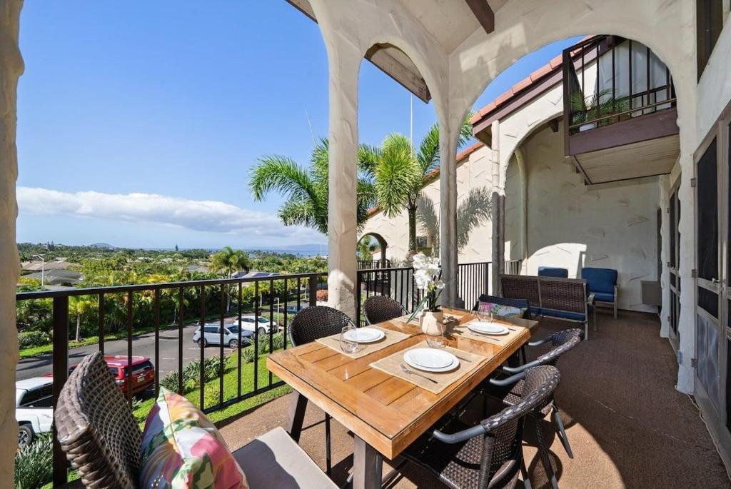 a patio with a wooden table and chairs on a balcony at Maui Hill 66 · MHL 66 3BD Condo Across from Keawakapu Beach & St in Wailea