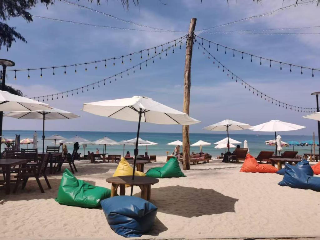 a sandy beach with tables and chairs and umbrellas at Seashell Family-222普吉岛木屋走几步到邦涛海滩看日落周边餐饮方便 in Bang Tao Beach