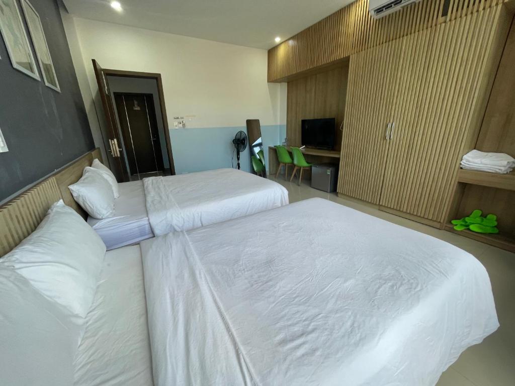 two beds in a hotel room with white sheets at Tự Do Homestay Huế in Hue