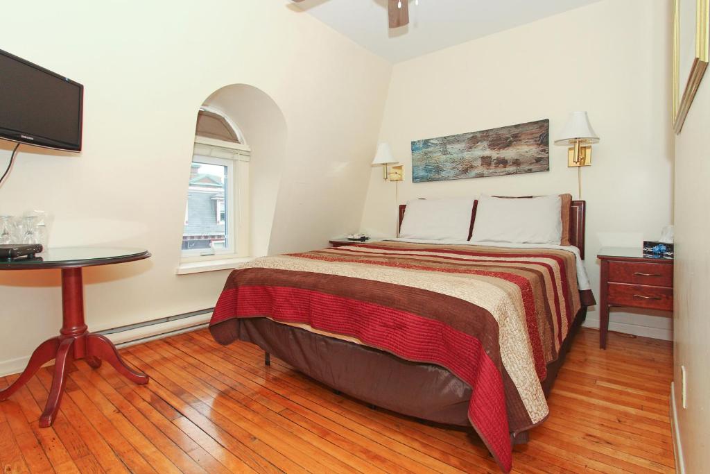 a bedroom with a bed and a table and a tv at Gower Guest House in St. John's