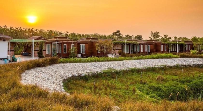 une rangée de maisons avec le coucher du soleil en arrière-plan dans l'établissement Prew Lom Chom Nam Resort, à Ban Phan Sadet Nai