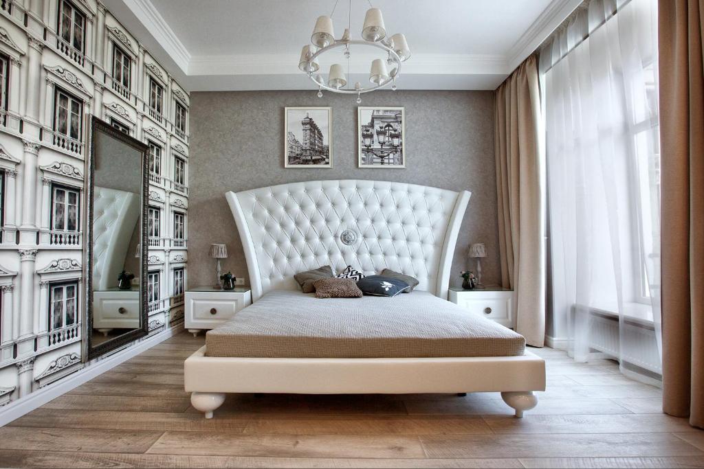 - une chambre avec un grand lit blanc et un lustre dans l'établissement Jane Stone Apartments, à Odessa