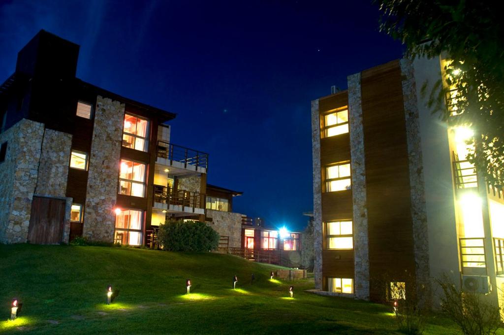 dos edificios por la noche con luces en el césped en Viñas del Mar Apart & SPA Aparthotel en Las Gaviotas