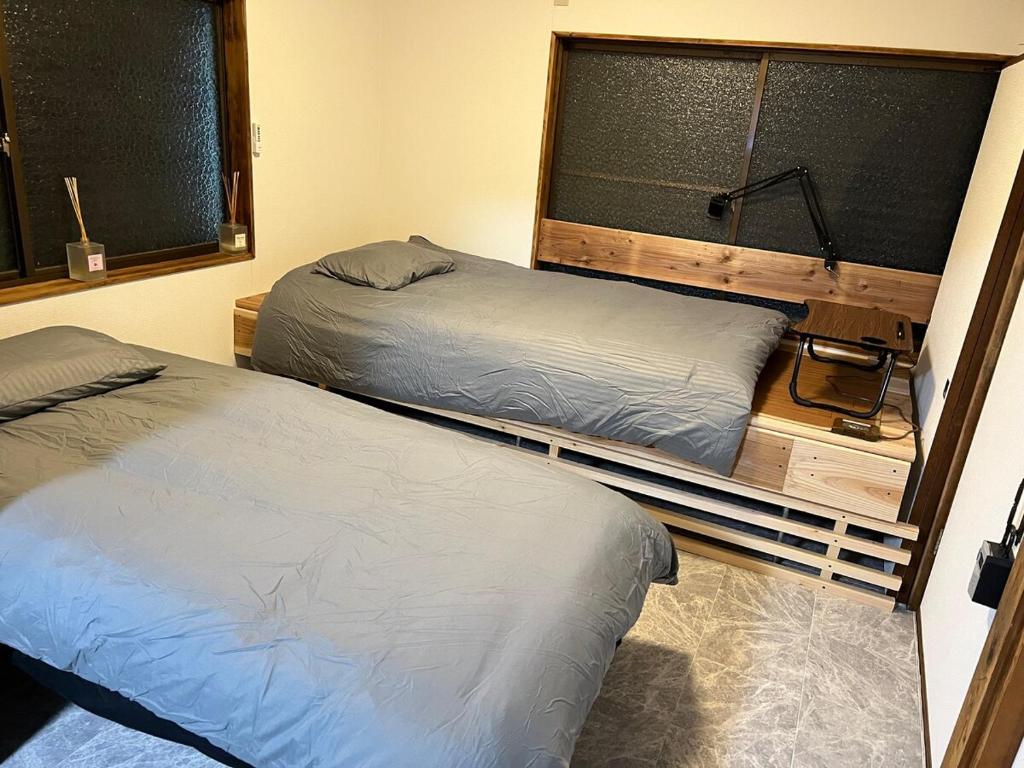 due letti singoli in una stanza con finestra di Village Misaki a Misaki