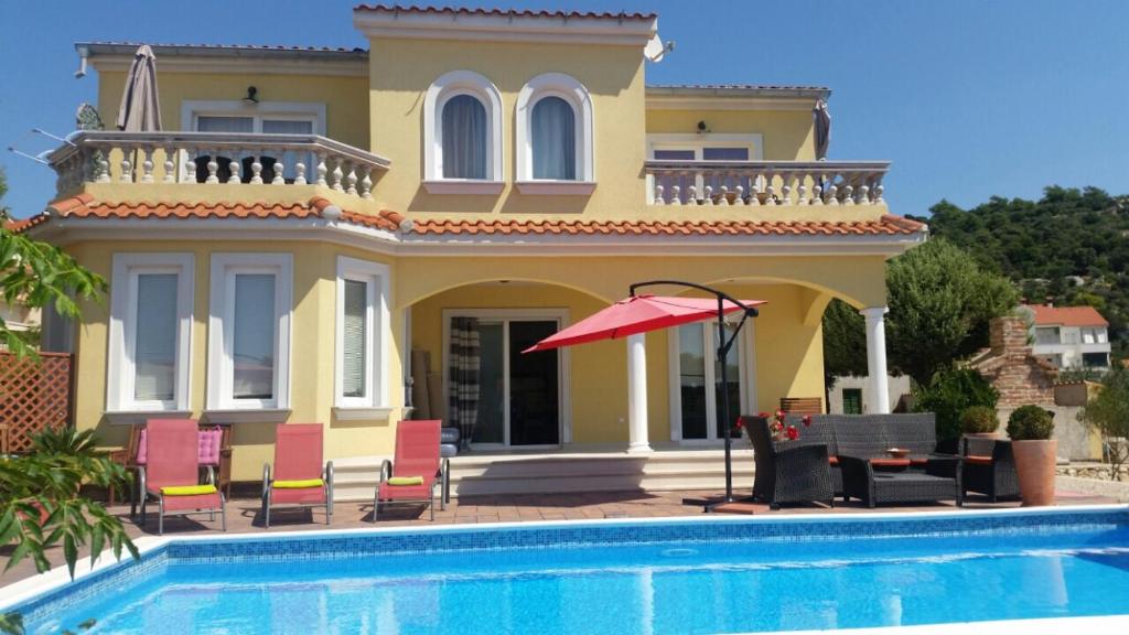 a villa with a swimming pool in front of a house at Villa Rosana in Rab