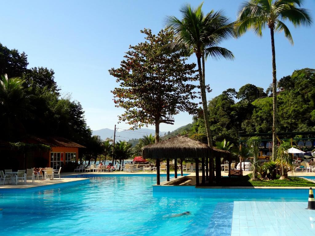 a swimming pool with palm trees and a resort at Casa Verde e Mar in Angra dos Reis