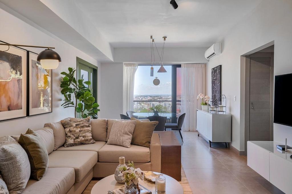 una sala de estar con un sofá y una mesa en ®{PANO~VIEW~Experience} @DowntownSD PoolGym2BR, en Ensanche Quisqueya