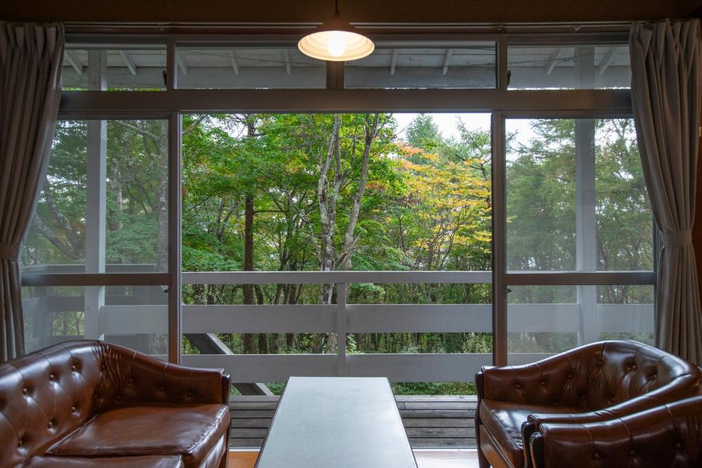 a living room with two leather chairs and a large window at rinne 2nd living Nasu Forest in Wada
