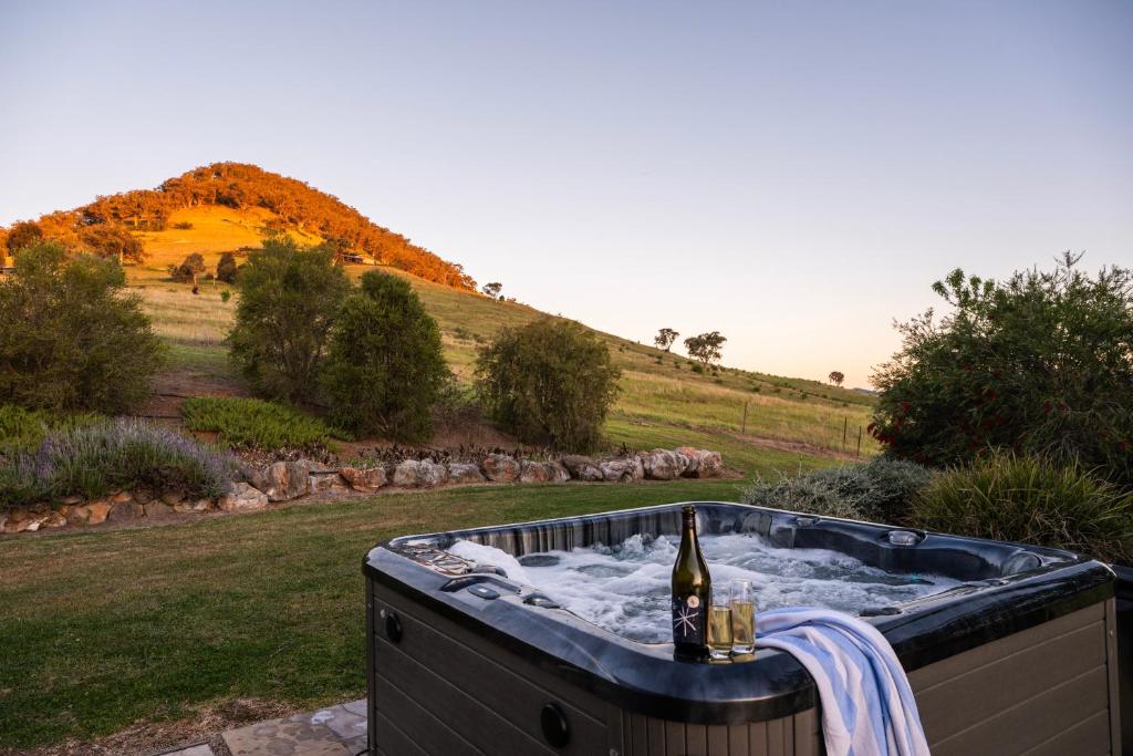 a hot tub with a bottle of wine in it at Allambie - Poolside Elegance in Mudgee Countryside in Mudgee