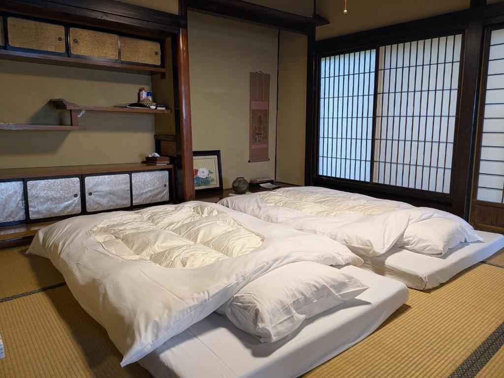 two beds in a room with white sheets and pillows at 信州の古民家宿 真秀ろばmahoroba in Nagano