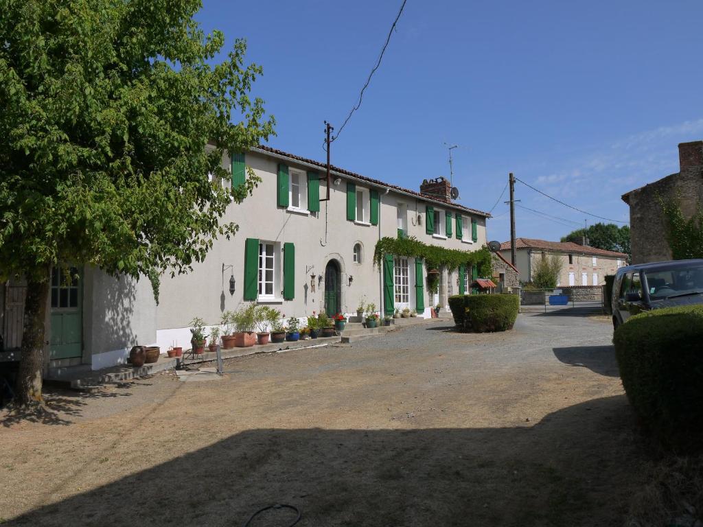 a white house with green shutters on a street at La Revaudiere in Bressuire