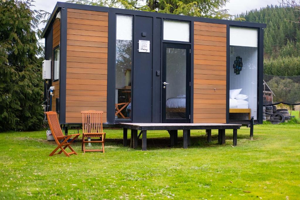 Una pequeña casa negra y de madera con mesa y sillas. en Lydia's Lodge by Tiny Away, en Belgrove