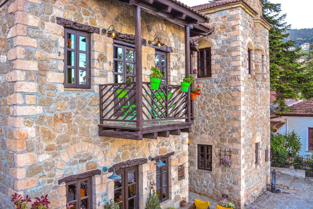 een stenen gebouw met een balkon met potplanten erop bij Varnevo Guesthouse in Ano Trikala