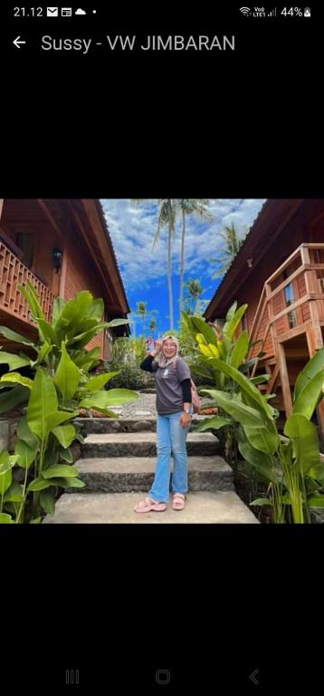 a woman standing on the stairs of a house at Pondok bluepo in Mendaya
