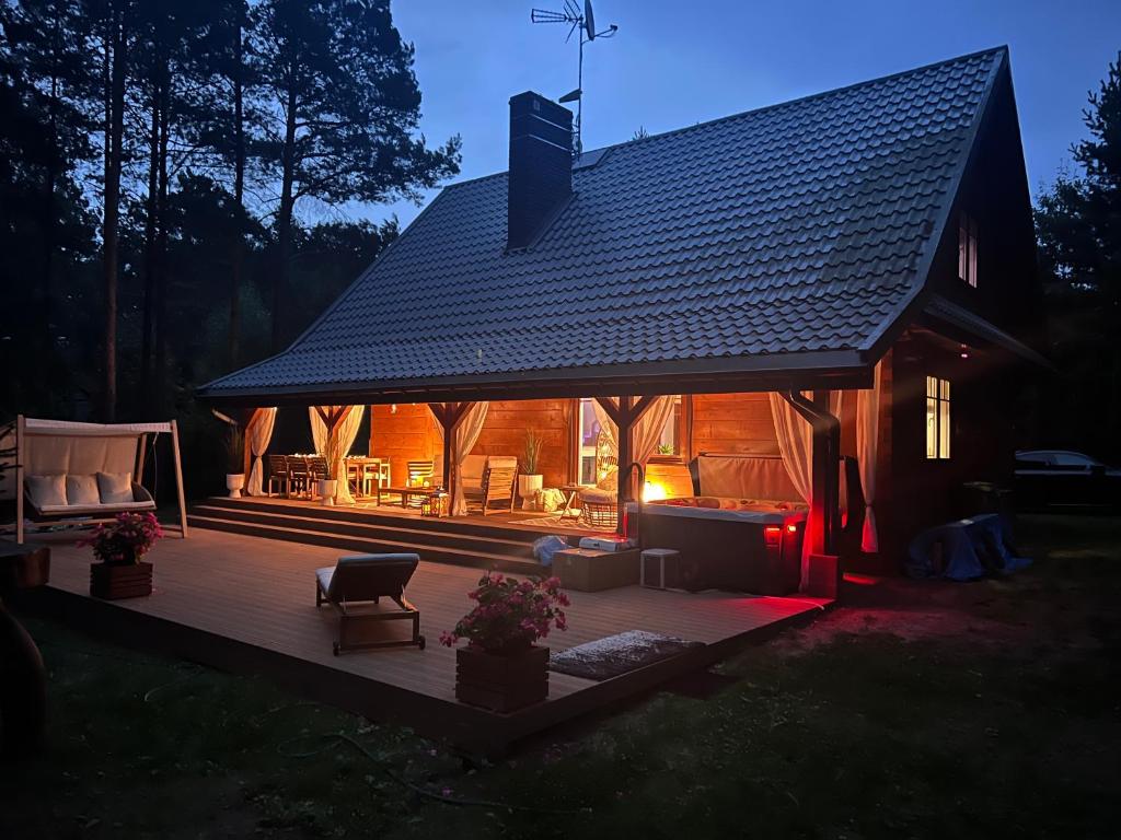 a large wooden deck with a house with a roof at Forest Home Dębowa 18 in Łuka