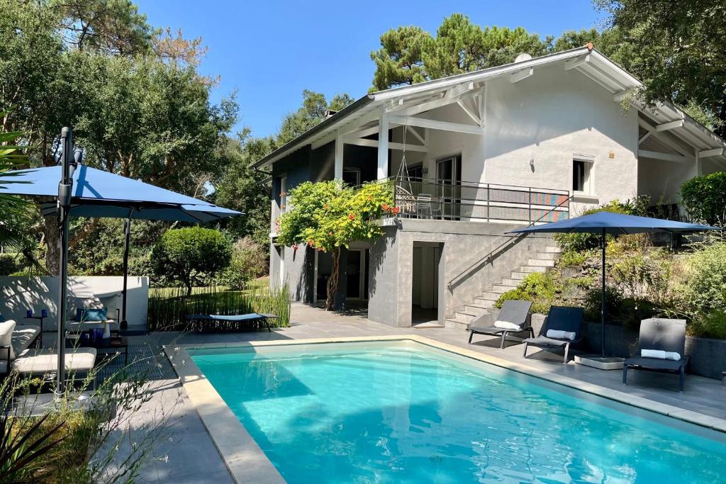 a house with a swimming pool with umbrellas at Villa Hortensia - Welkeys in Soorts-Hossegor