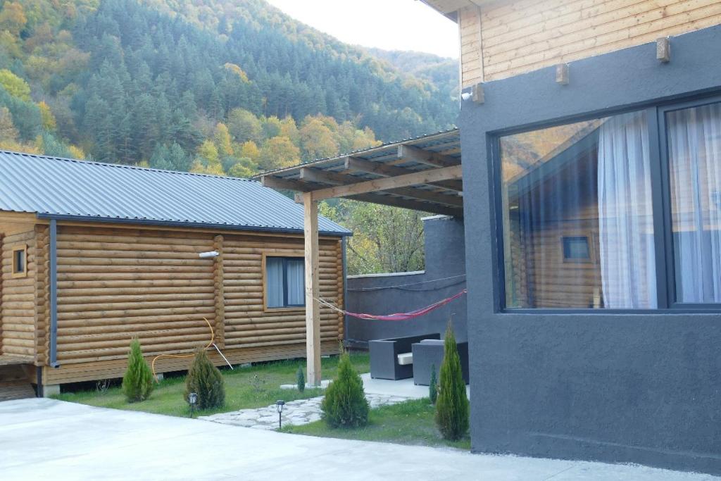 a log cabin with a red rope hanging from a building at Khando's Resort in Passanauri