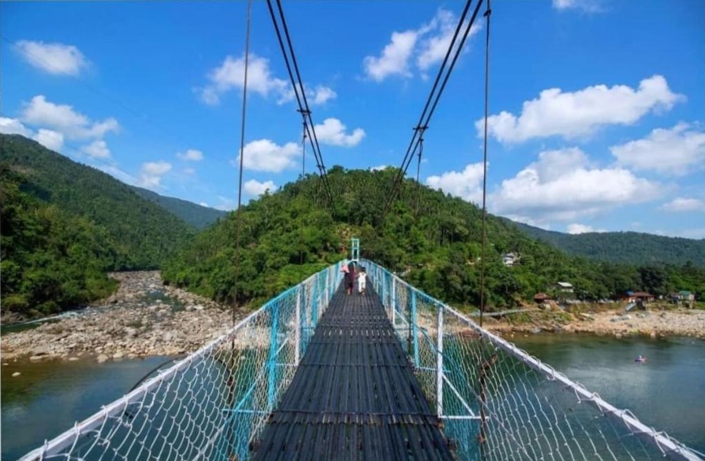 eine Person, die über eine Hängebrücke über einen Fluss geht in der Unterkunft Vicky camps & Adventures in Shillong