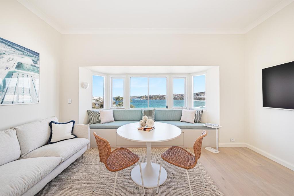 a living room with a couch and a table and chairs at Beachfront 1 Bed across from iconic BONDI BEACH in Sydney