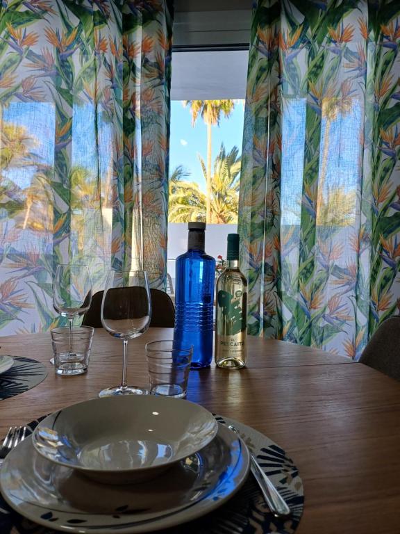 un tavolo di legno con un piatto e due bottiglie di vino di Casa Esterlita a Tarajalejo