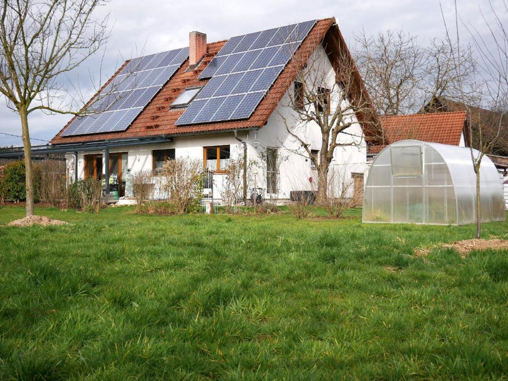 une maison avec des panneaux solaires sur le toit et une serre dans l'établissement Ferienwohnung Obere Alm, à Ödsbach