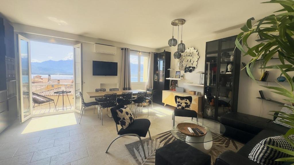 a living room with a table and chairs and a large window at Appartement Le Millie 3 chambres Hyper centre in Calvi