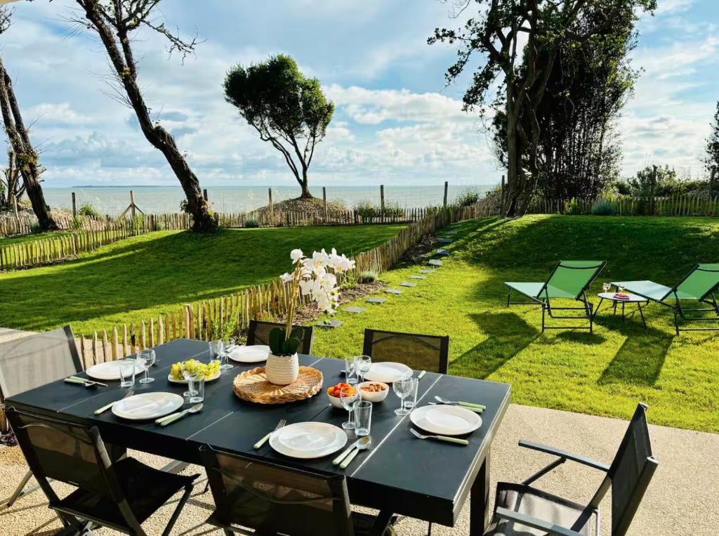 une table noire et des chaises avec vue sur l'océan dans l'établissement Séjour prestige - vue mer et accès privé à l'océan, à Angoulins-sur-Mer