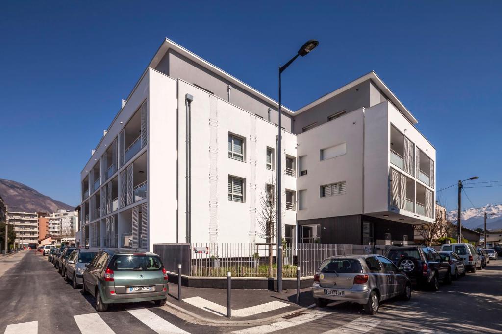 um edifício branco com carros estacionados num parque de estacionamento em Tempologis Grenoble em Grenoble