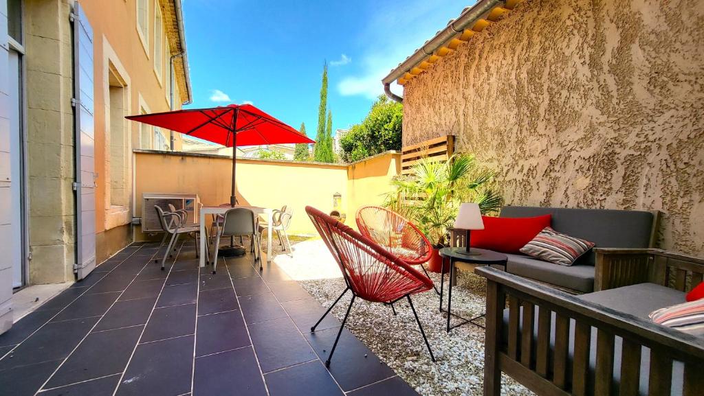 eine Terrasse mit einem roten Regenschirm, einem Tisch und Stühlen in der Unterkunft Maison de village façon Loft, avec cour et airco, dans le centre historique in LʼIsle-sur-la-Sorgue