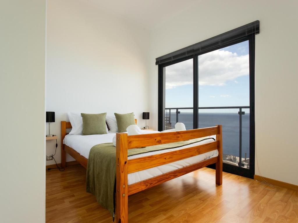 a bedroom with a bed and a large window at Skyline Villas RC in Arco da Calheta