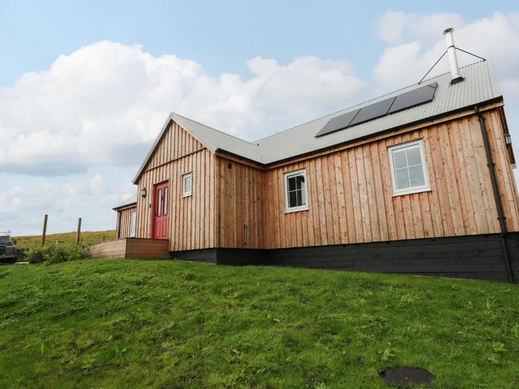 a wooden house with a red door on a grass field at Tirlaggan Úr in Oban