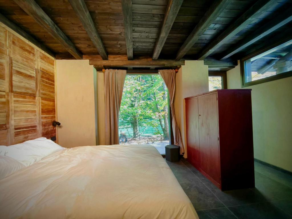 een slaapkamer met een groot bed en een groot raam bij Rèfol Lodge Val di Ledro in Pur