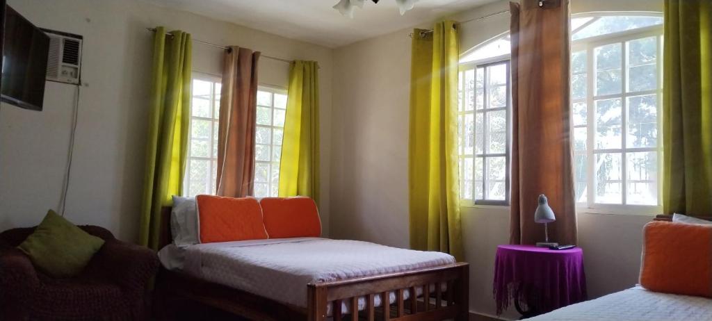 a room with two beds and windows with yellow curtains at Boquete Guest House in Puente Cochea