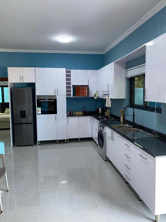 a large kitchen with white appliances and blue walls at Villa Djonasse, a Residence of Exellency in Fombeni