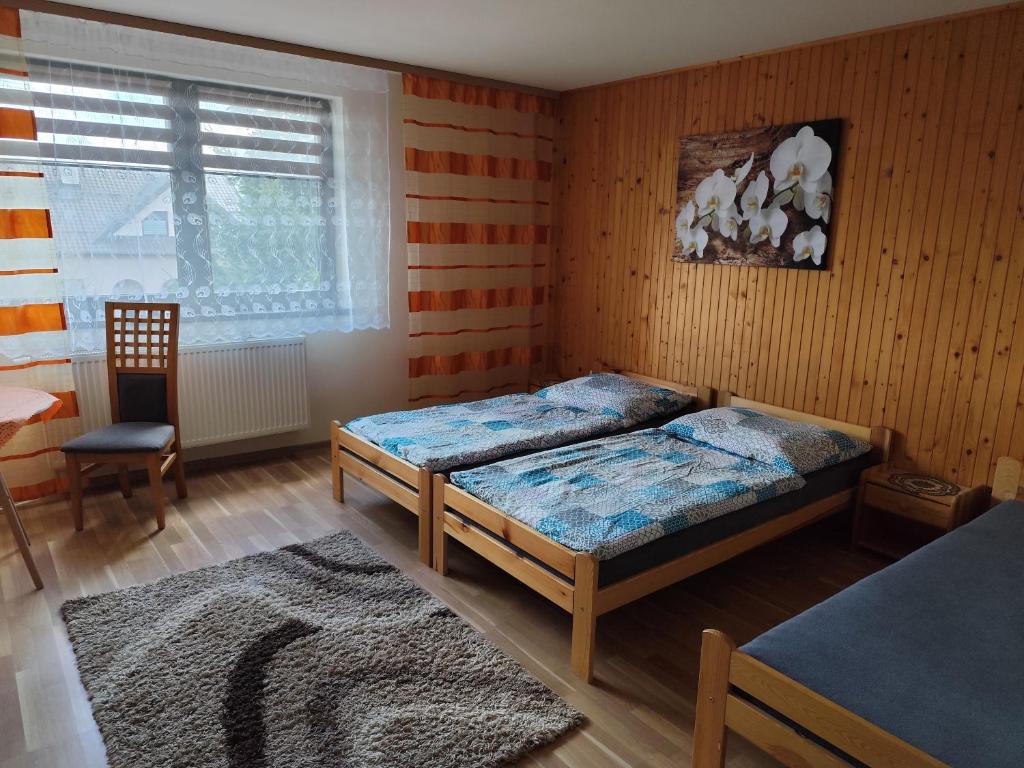 een slaapkamer met twee bedden en een stoel en een raam bij Sárka in Štrba