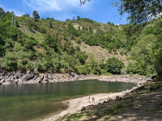 a body of water next to a hill with trees at Casa da Edrada 