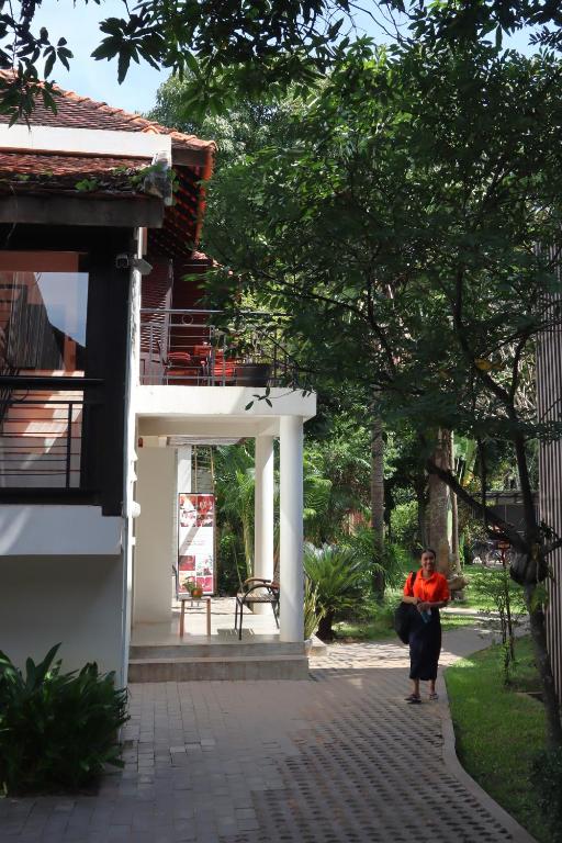 a woman walking down a walkway next to a building at Sala Baï Hotel & Restaurant School in Siem Reap