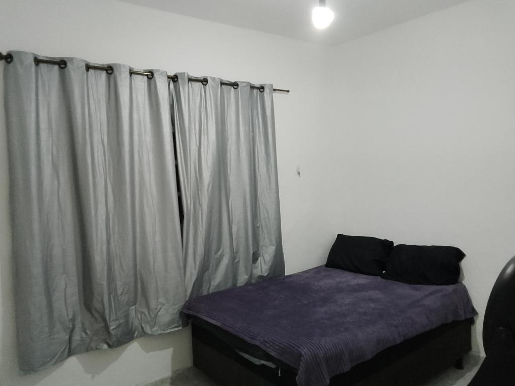 een bed in een kamer met een raam met gordijnen bij Casas Mobiliadas in Aracaju