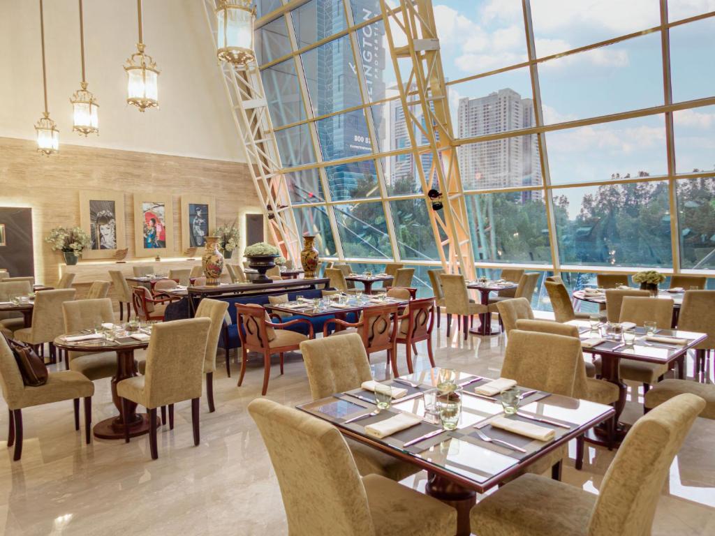a restaurant with tables and chairs and large windows at Grand Millennium Dubai in Dubai