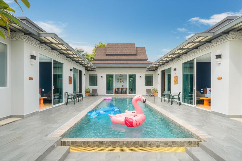 a pool with two inflatable flamingos in a house at Phuket La Siesta Pool Villas & Pool Access Rooms in Nai Harn Beach