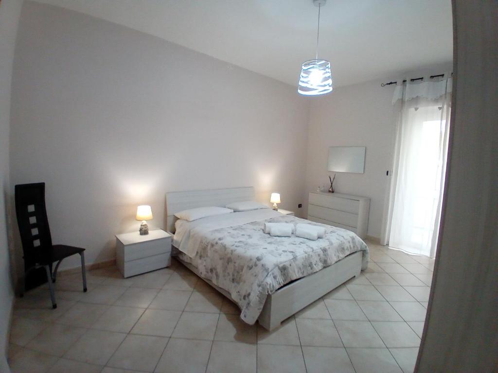 a white bedroom with a bed and a chair at SA HOUSE in Barletta