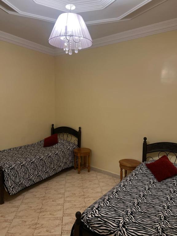 a room with two beds and a chandelier at Villa nuira in Inezgane
